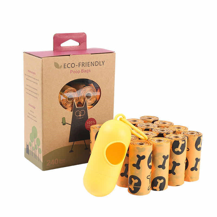 Eco-friendly dog poop bag set with 16 rolls of orange bags featuring black bone prints, yellow clip-on dispenser, and cardboard packaging with a cut-out window showing the rolls