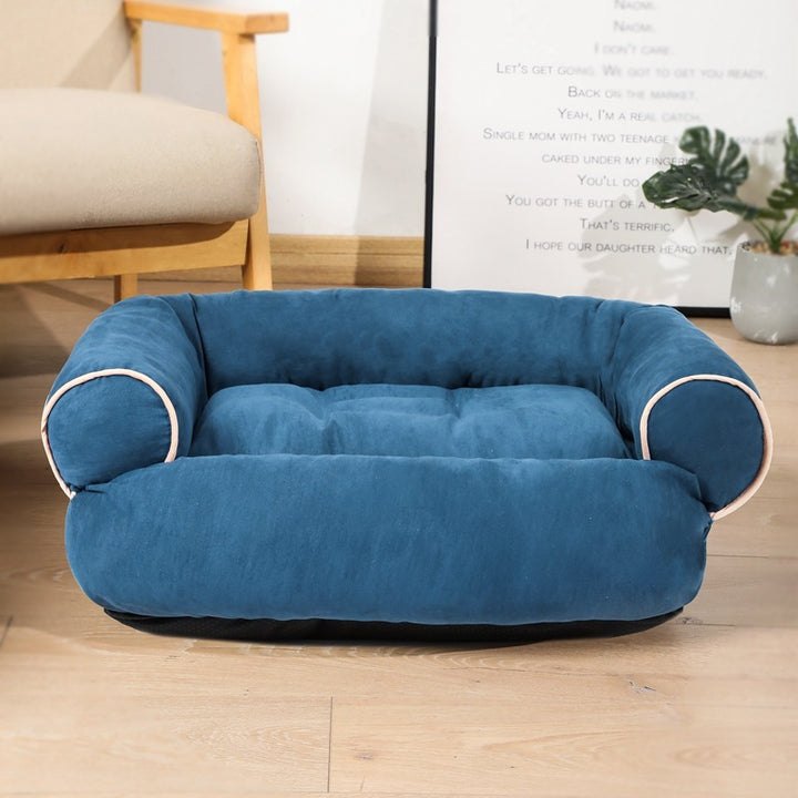 Blue pet bed on a wooden floor with a chair and plant in the background