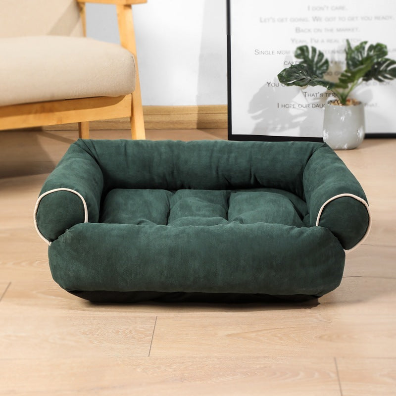 Green pet bed on a wooden floor with a chair and plant in the background