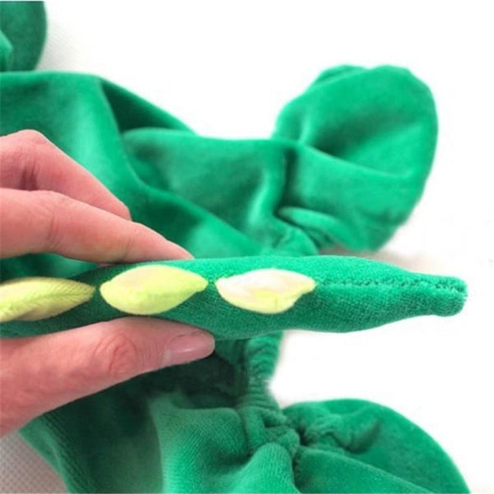 Green plush toy with a hand holding one of its legs on a white background