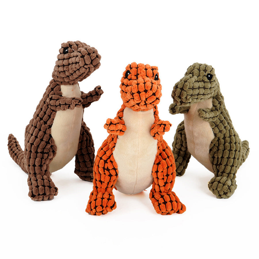 Three dinosaur-shaped dog toys in brown, orange, and green on a white background