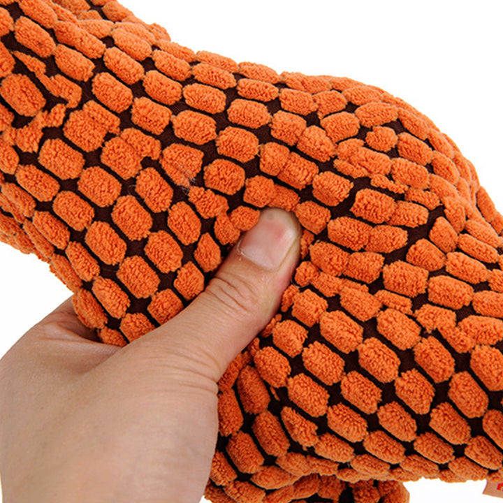 Orange textured dog toy held by a hand against a white background