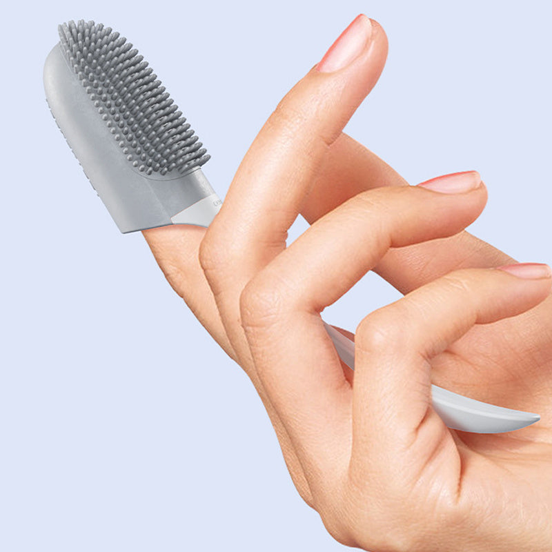 Hand holding a small gray pet tooth brush against a light blue background