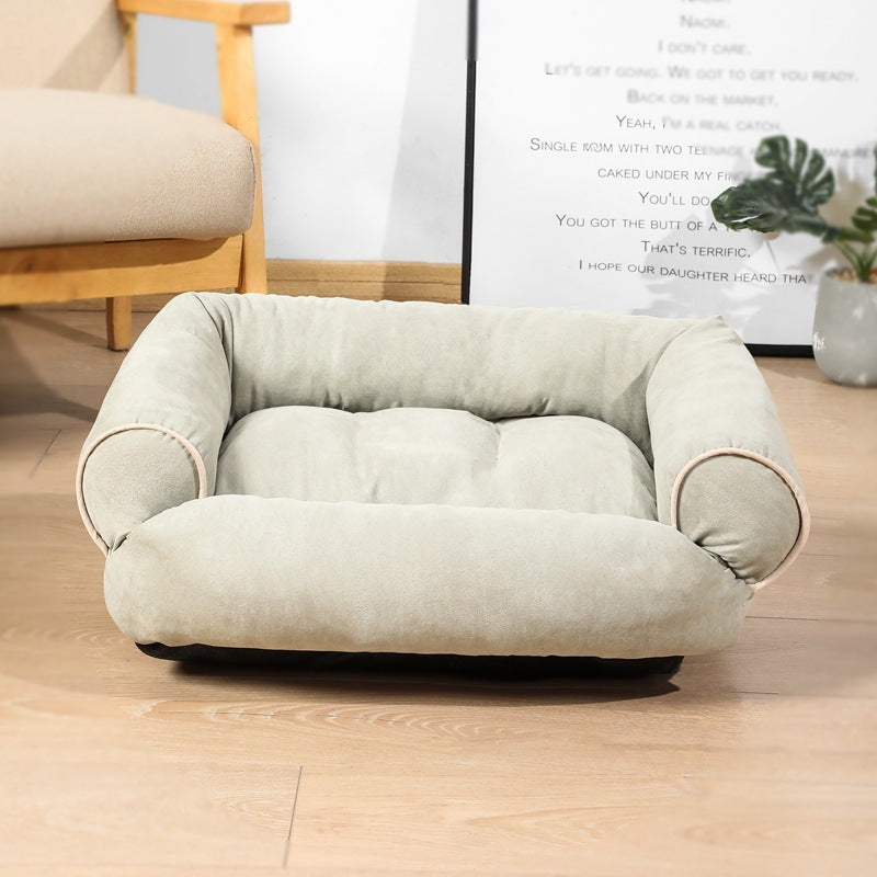 Light gray pet bed on a wooden floor with a chair and plant in the background