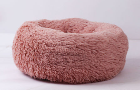 Pink fluffy donut-shaped pet bed on a white background