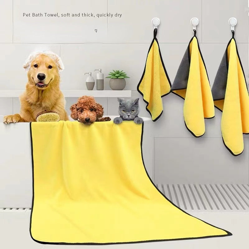 Yellow pet bath towel draped over a dog, with three hanging towels on a wall.