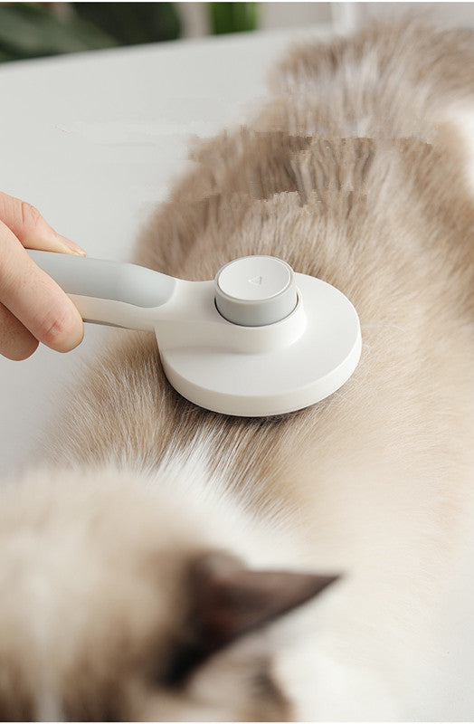 Person using a white pet grooming tool on a cat's fur