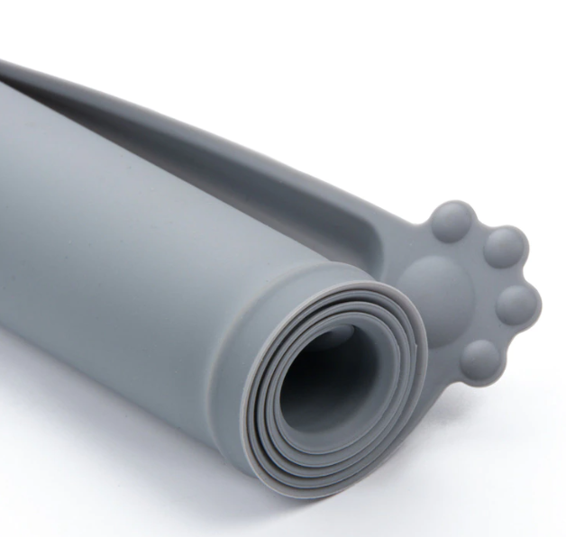 A rolled-up silicone pet bowl mat with a raised lip, typically used to contain bowls and prevent spills.