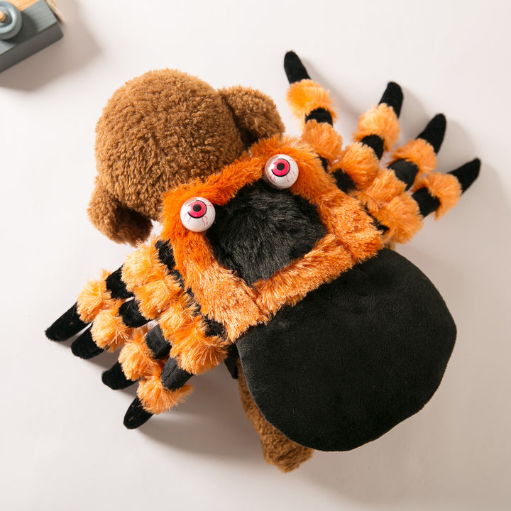 Plush toy resembling a spider with orange body, black legs, and brown head on a white background
