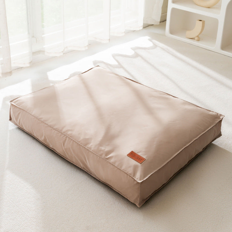Beige pet bed with a small brown label on a light wooden floor.