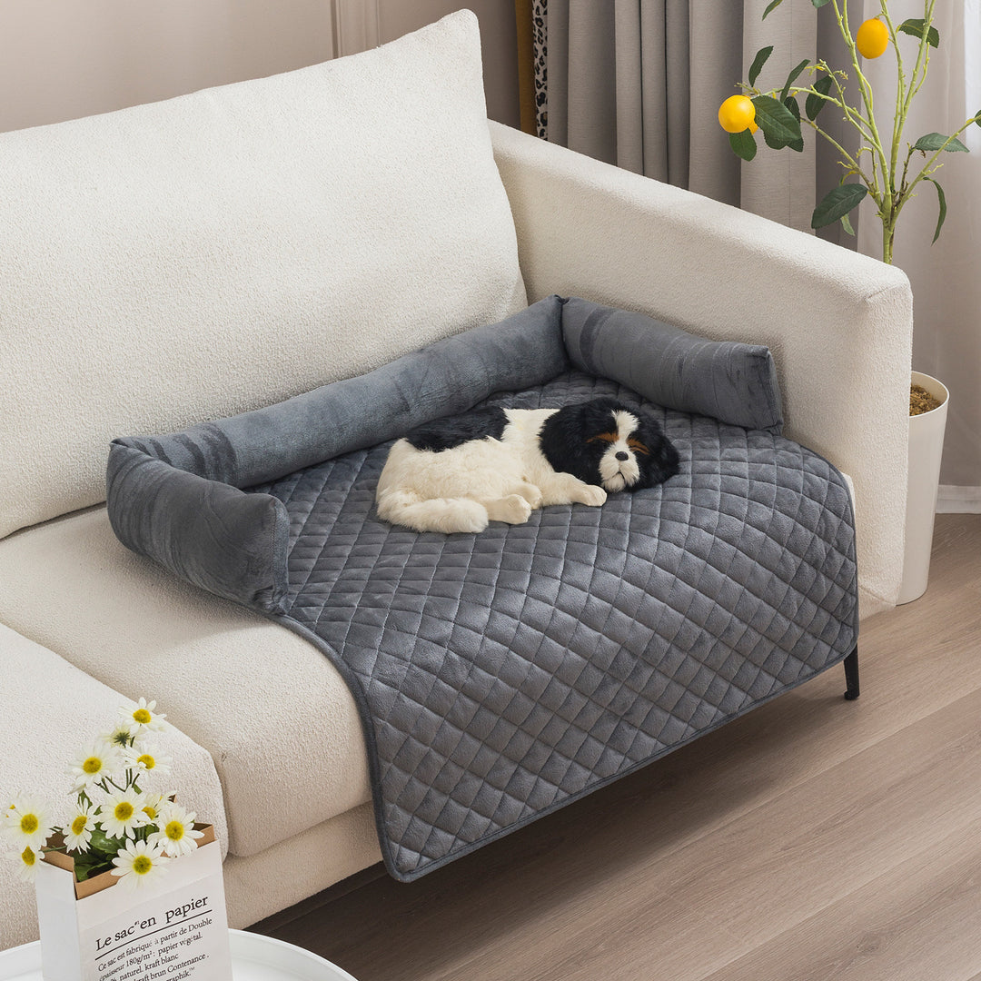 Dog lying on a gray pet bed attached to a white couch in a living room.