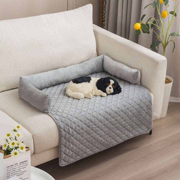 Dog lying on a gray pet bed attached to a couch in a living room.