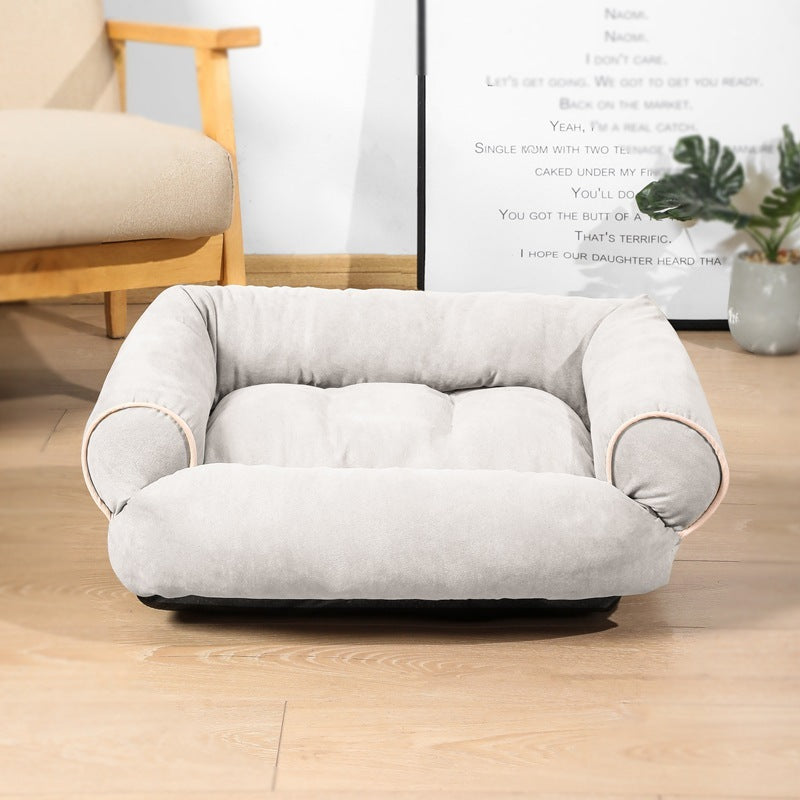Gray pet bed on a wooden floor with a chair and plant in the background