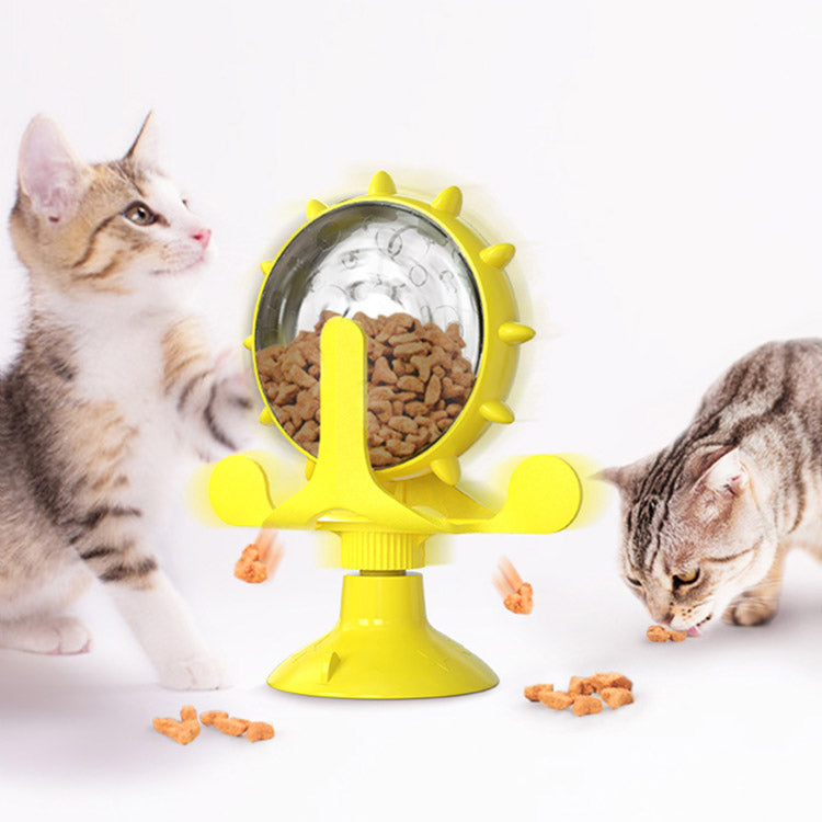 Yellow pet toy with a transparent center filled with cat food, with two cats interacting with it.