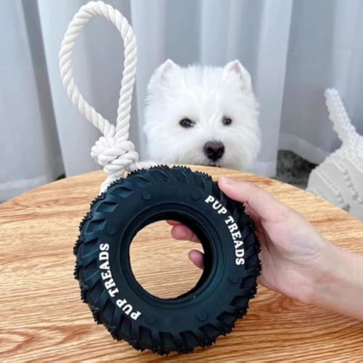 Dog toy with a rope and 'PUP TREADS' branding held by a hand, with a dog in the background.
