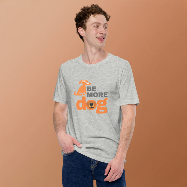Man wearing a gray t-shirt with 'Be More Dog' text and graphic on a brown background