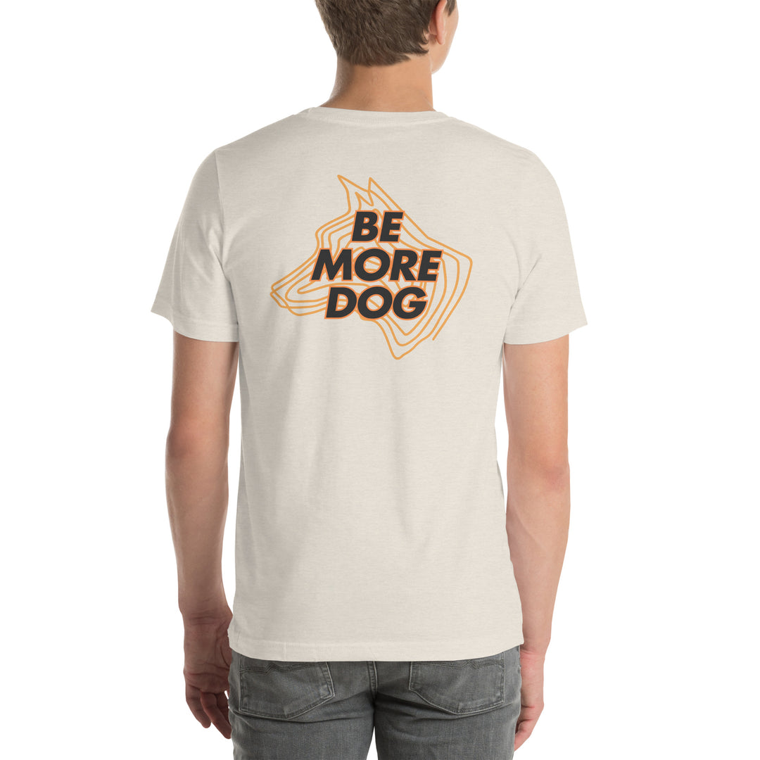 Person wearing a beige t-shirt with 'Be More Dog' print on the back