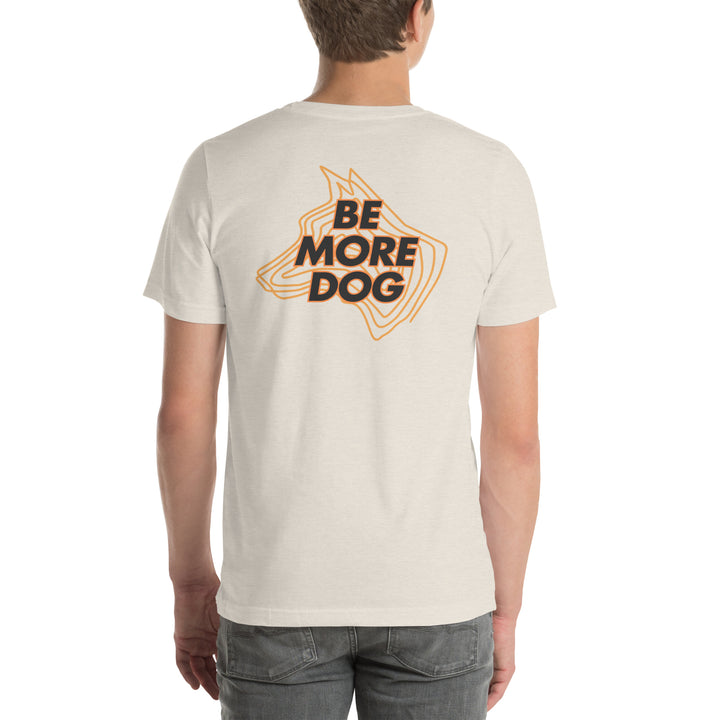 Person wearing a beige t-shirt with 'Be More Dog' print on the back
