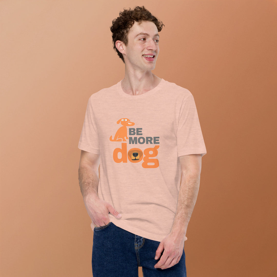 Person wearing a peach t-shirt with 'Be More Dog' text and graphic on a brown background
