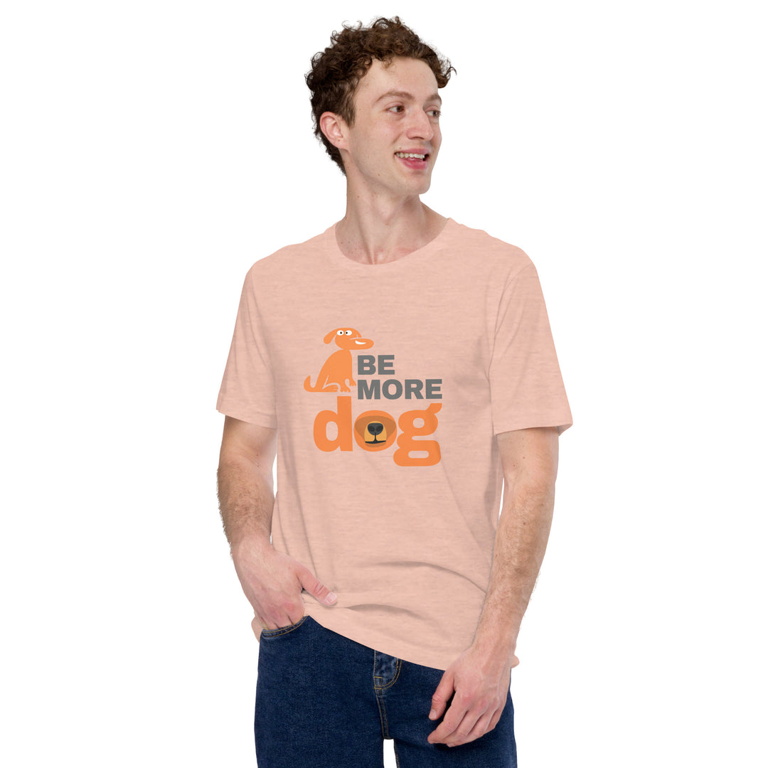 Person wearing a peach t-shirt with 'Be More Dog' text and graphic on a white background