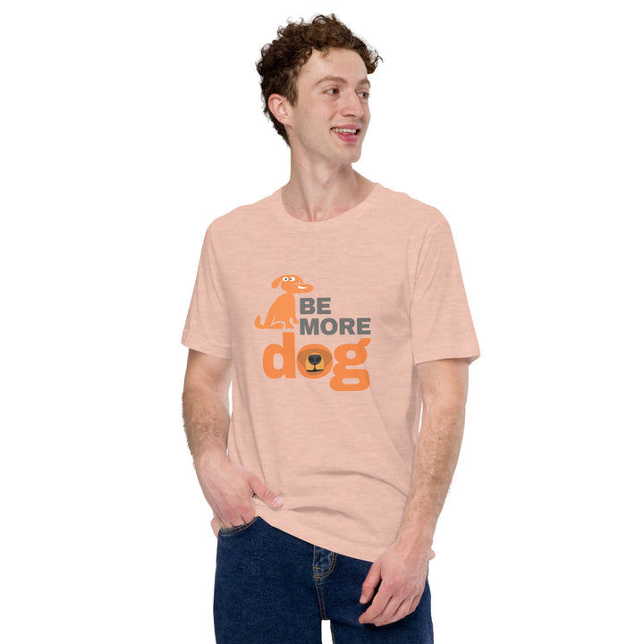 Person wearing a peach t-shirt with 'Be More Dog' text and graphic on a white background